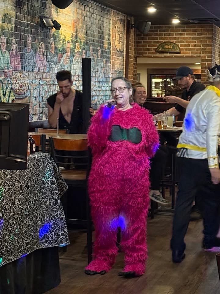 Guest in a bright pink costume enjoying a karaoke night
