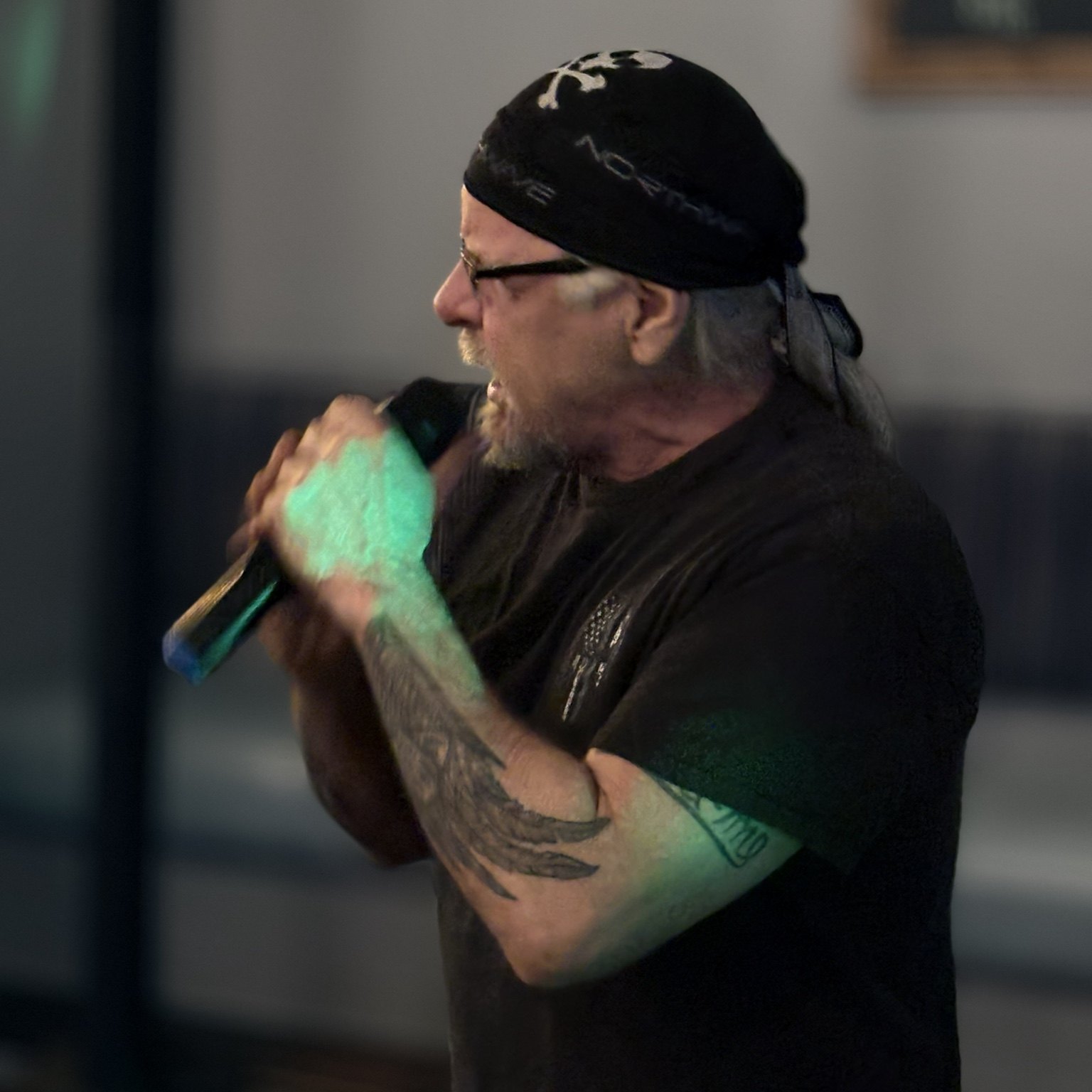 Karaoke singer in a cap holding a microphone under stage lights
