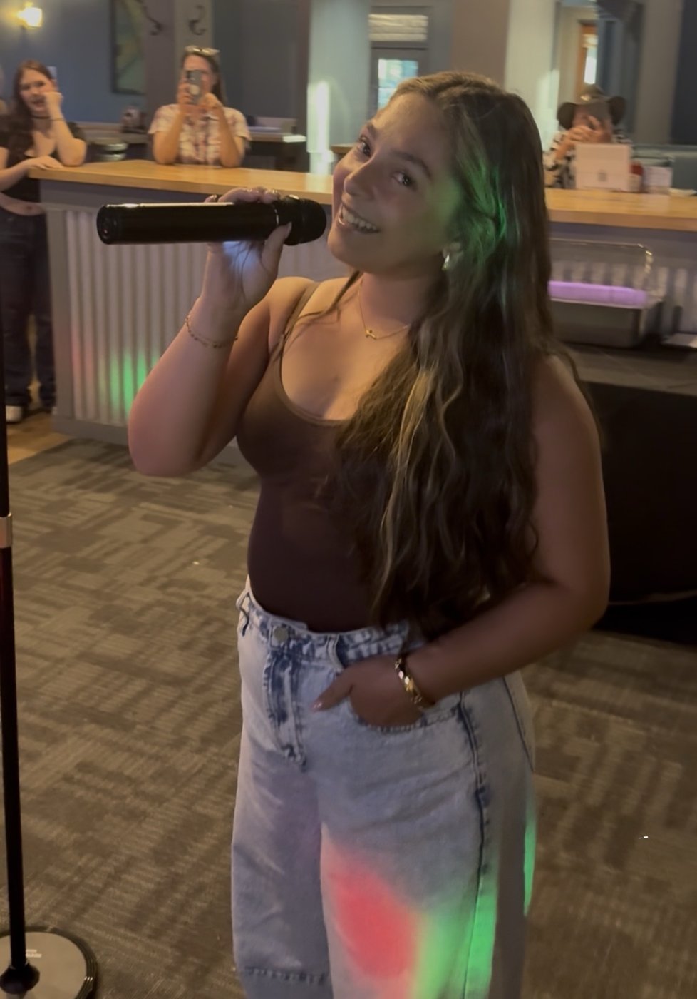 A singer holding a microphone under colorful lights